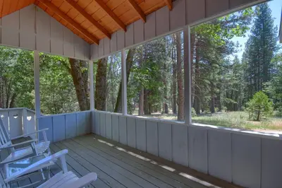 a screened porch with two rocking chairs and trees at 43R Edna's Hearts Desire in North Wawona