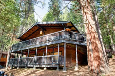 a cabin in the woods with a wrap around deck at 18B Hiltbrand Hangout in Wawona