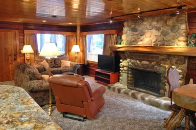 a living room with a stone fireplace and a television at 79 Half Dome in Wawona