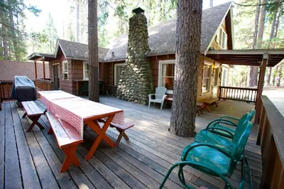 a wooden deck with a table and chairs on a cabin at 80 Chattertons Cottage in North Wawona