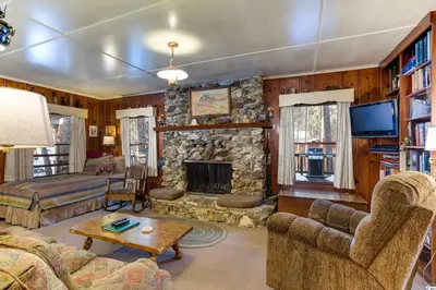 a living room with a stone fireplace and a tv at 80 Chattertons Cottage in North Wawona