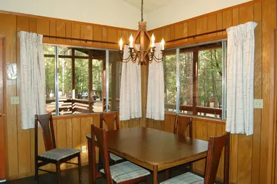a dining room with a table and chairs and windows at 84 Hastings Hideaway in Wawona