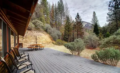 a wooden deck with chairs and a table on it at 17A Longview in Wawona