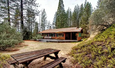 a log cabin with a picnic bench in front of it at 17A Longview in Wawona