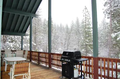 a screened in porch with a grill and snow covered trees at 44R Grant's Camp in Wawona