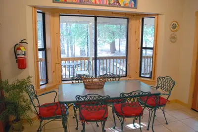 a screened in porch with a table and chairs at 93 Doyles Mountain in Wawona