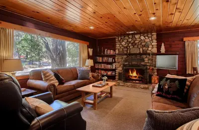 a living room with leather furniture and a stone fireplace at 57 The Williams Cabin in Wawona