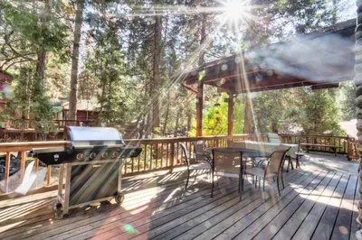 a grill on a deck with a table and chairs at 7 Cedar Lodge in Wawona