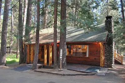 a log cabin in the woods with trees at 52 Tuolumne Meadow in Wawona