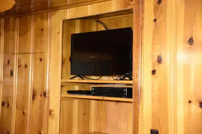 a entertainment center with a television in a wooden wall at 52 Tuolumne Meadow in Wawona