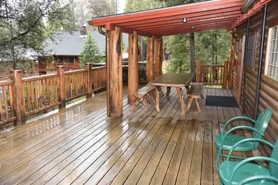a wooden deck with a table and chairs on it at 52 Tuolumne Meadow in Wawona