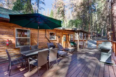 a deck with a table and chairs and an umbrella at 74 Our Yosemite Getaway in Wawona