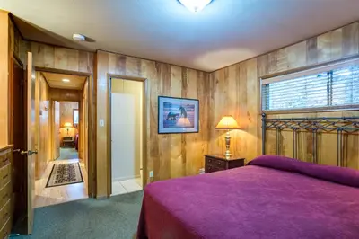 a bedroom with a purple bed and wooden walls at 64 River Lodge in North Wawona