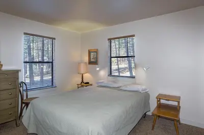 a white bedroom with a bed and two windows at 1A Wawona Retreat in Wawona