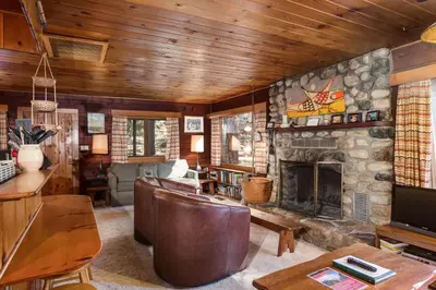 a living room with a stone fireplace and a couch at 53 Creekside Cabin in Wawona