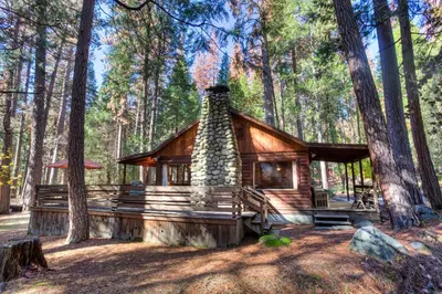a log cabin in the middle of a forest at 53 Creekside Cabin in Wawona