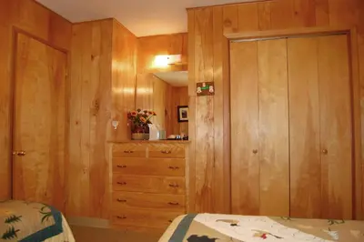 a bedroom with wooden walls and a dresser and a bed at 82 Shehadey's Retreat in North Wawona