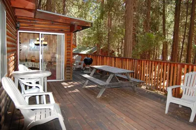 a wooden deck with a picnic table and chairs on a cabin at 82 Shehadey's Retreat in North Wawona