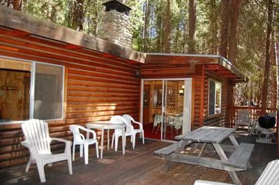 a wooden cabin with a table and chairs on a deck at 82 Shehadey's Retreat in North Wawona