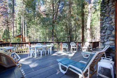 a deck with a table and chairs and trees at 55 Deer Creek in Wawona