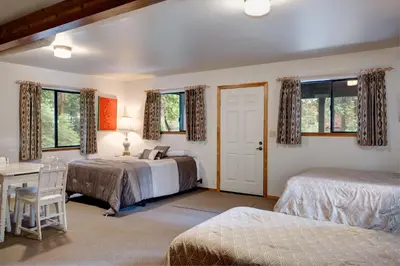a bedroom with two beds and a desk and windows at 1S Cecils Cabin in South Wawona