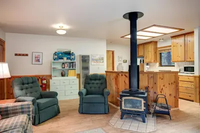 a living room with a stove and two chairs at 1S Cecils Cabin in South Wawona