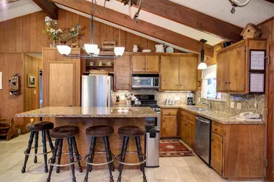 a kitchen with wooden cabinets and a island with bar stools at 12B Star Gazers in Wawona