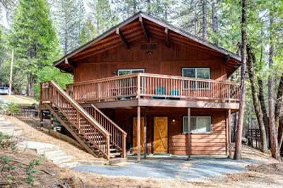 a cabin in the woods with a large deck at 12B Star Gazers in Wawona