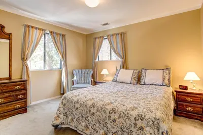 a bedroom with a bed and a chair and windows at 1 Cabin Among the Firs in Wawona