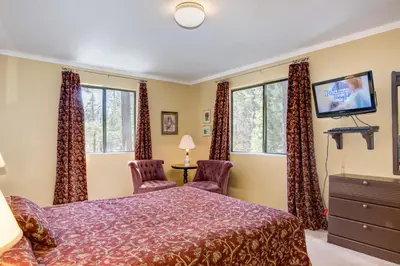 a bedroom with a bed and two chairs and a tv at 1 Cabin Among the Firs in Wawona