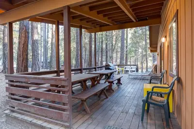 a porch of a cabin with wooden tables and chairs at 3A Cutters Edge in Wawona