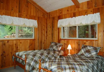 two beds in a room with wooden walls and windows at 30A Dunnings Retreat in Wawona