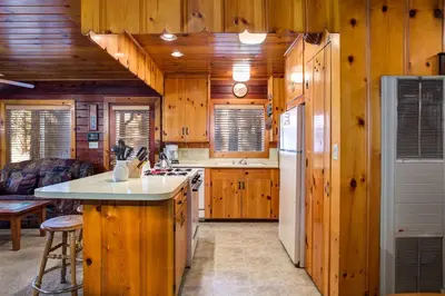 a kitchen with wooden walls and a refrigerator and a counter at 70 Simmons Den in Wawona