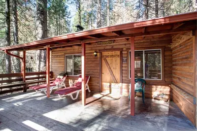 a cabin in the woods with chairs and a porch at 70 Simmons Den in Wawona