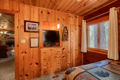 a bedroom with a tv in a wooden wall at 73 Walk-A-Bout in Wawona