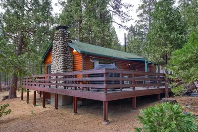 a log cabin with a large deck in the woods at 73 Walk-A-Bout in Wawona