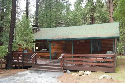 a cabin in the woods with a large deck at 73 Walk-A-Bout in Wawona