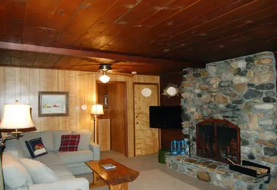 a living room with a couch and a stone fireplace at 6 Squirrels Nest in Wawona