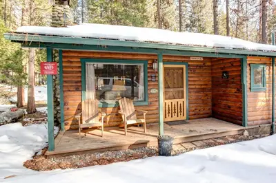 a log cabin with a deck in the snow at 59 Hansen Cabin in North Wawona