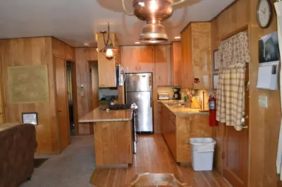 a kitchen with wooden cabinets and a stainless steel refrigerator at 23 Arnetts Cabin in North Wawona