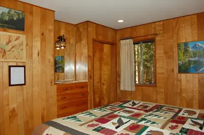 a bedroom with wooden walls and a bed and a window at 23 Arnetts Cabin in North Wawona