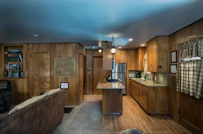 a kitchen with wooden cabinets and a couch in a room at 23 Arnetts Cabin in North Wawona