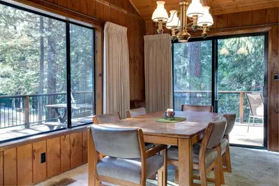 a dining room with a table and chairs and large windows at 40 Coyles Cabin in Wawona