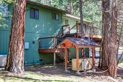 a green house with a staircase and a tree at 40 Coyles Cabin in Wawona