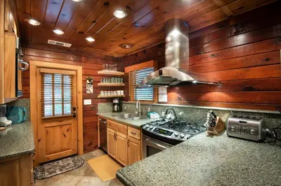 a kitchen with wooden walls and a stove top oven at 48 Sugar Pine Suite in North Wawona