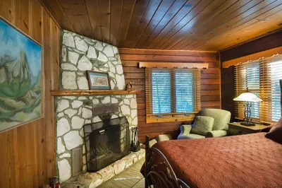 a bedroom with a stone fireplace with a bed and a chair at 48 Sugar Pine Suite in North Wawona