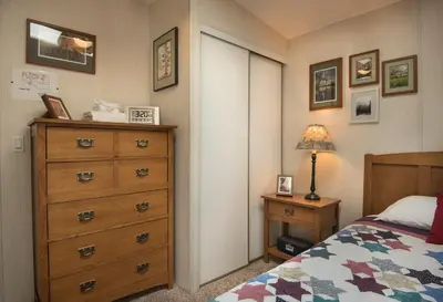 a bedroom with a bed and a dresser with a lamp at 42R Rosenberg's Creekside Cabin in Wawona
