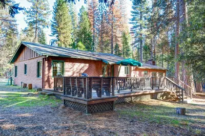a cabin in the woods with a large deck at 81 Ashbaugh Meadow in North Wawona