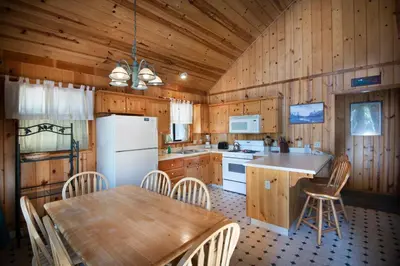 a kitchen with a table and a white refrigerator at 24 Wawona Cabin in Wawona
