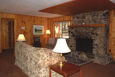 a living room with a couch and a stone fireplace at 9S Pine Cabin in South Wawona